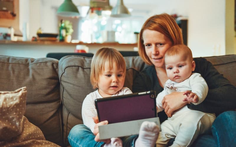 Moeder leest samen met haar twee kinderen op de bank